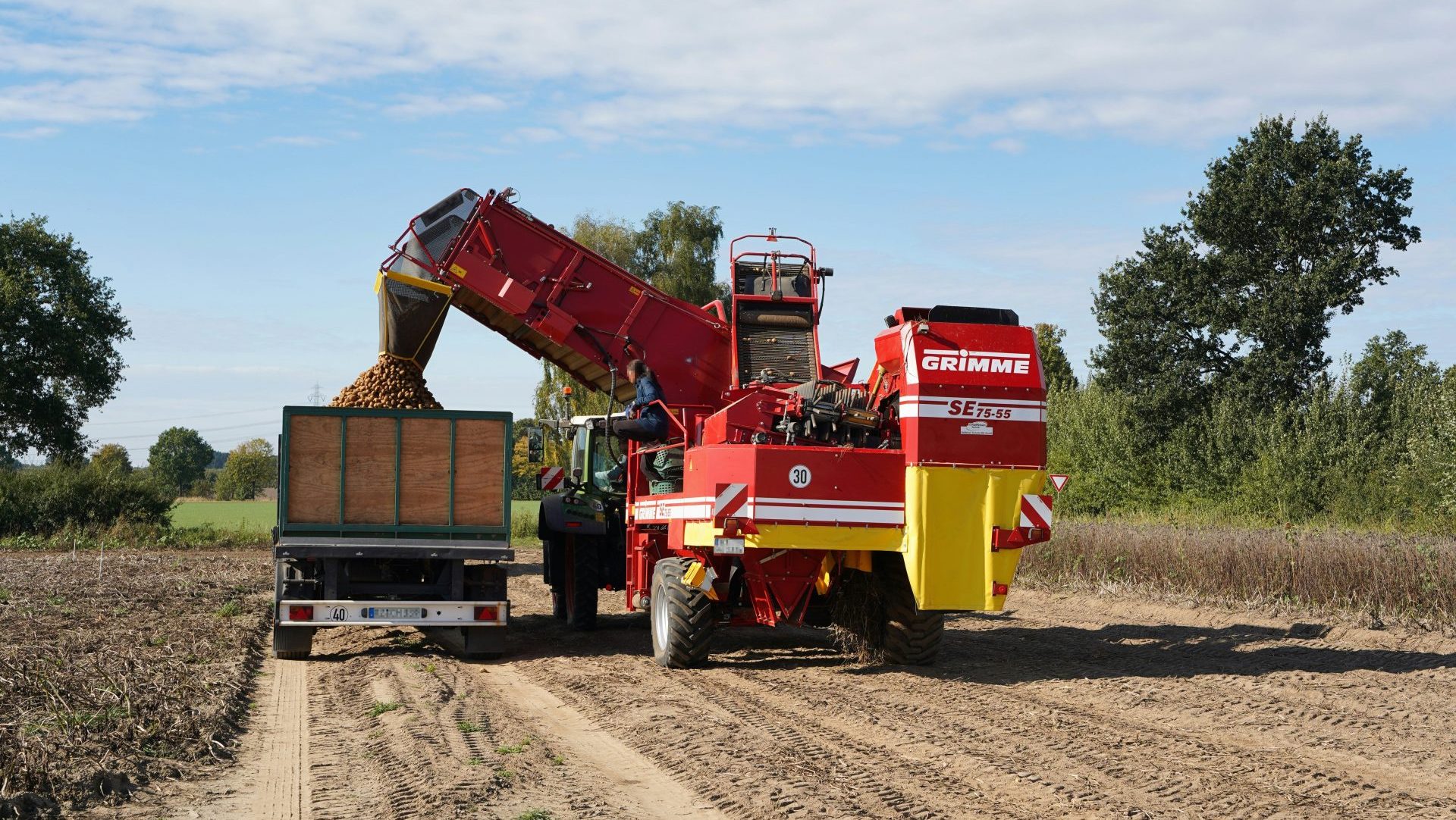 Harvester machine unloading potatoes into a trailer